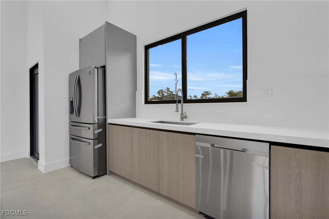 1011 State Avenue Lehigh Acres, FL 33972 - Photo 13 of 34 a kitchen with stainless steel appliances a refrigerator and a window