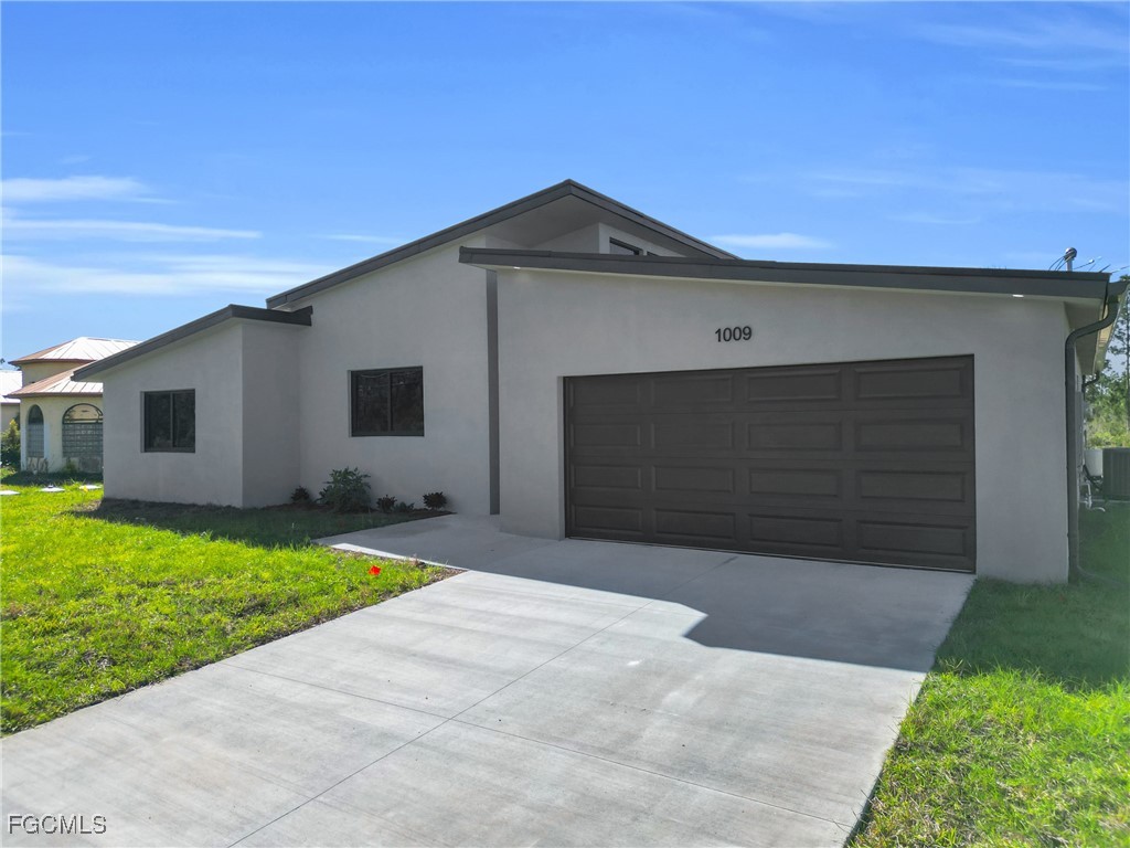 1011 State Avenue Lehigh Acres, FL 33972 - Photo 3 of 34 a front view of a house with a yard and garage