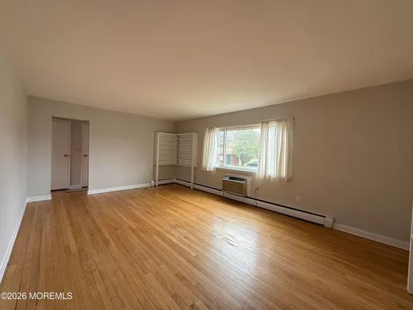 a view of an empty room with wooden floor and a window