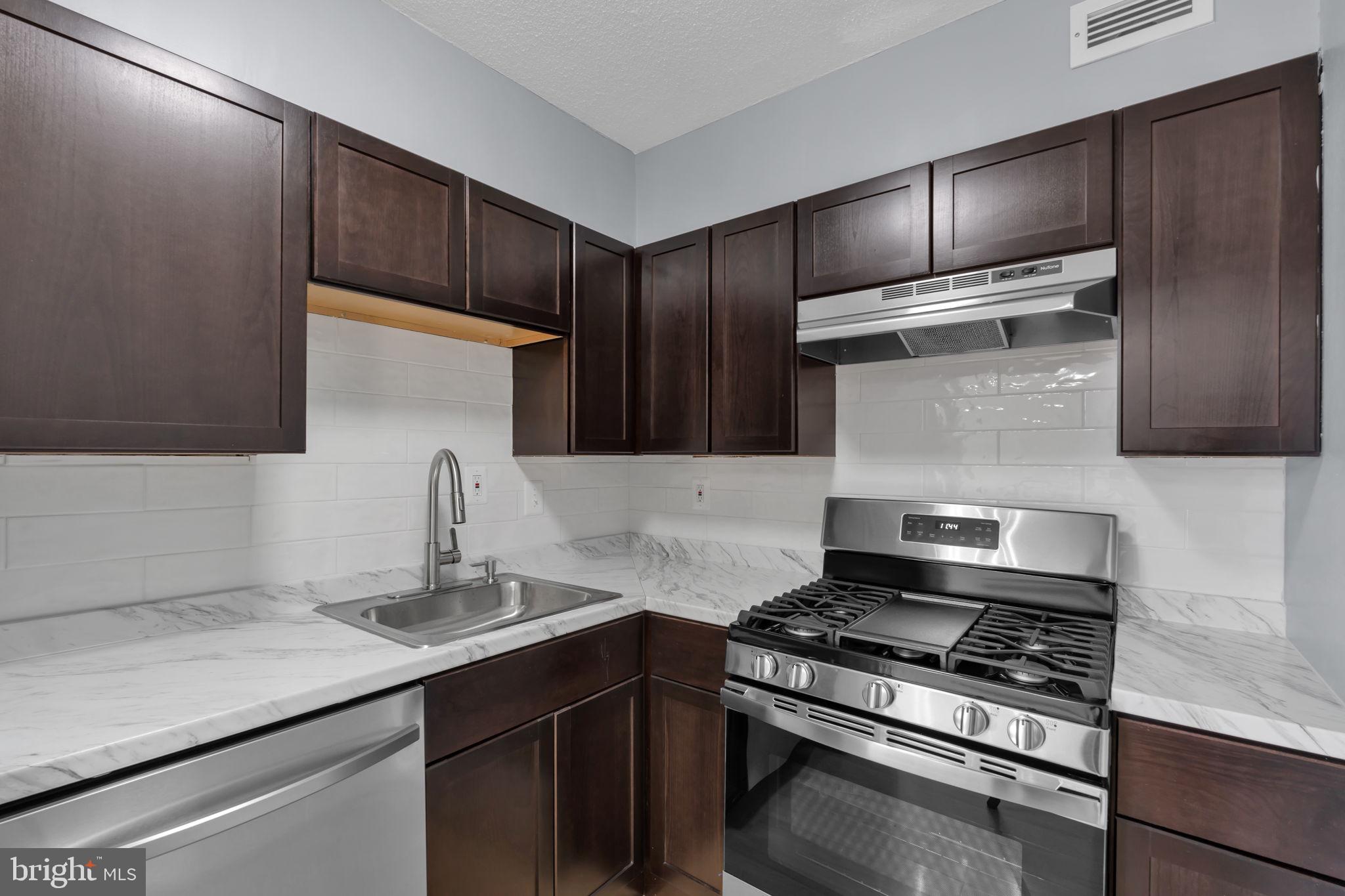 1245 4th Street Southwest, Unit E210 Washington, DC 20024 - Photo 13 of 28 a kitchen with stainless steel appliances granite countertop a sink stove and refrigerator