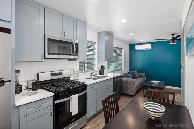 a kitchen with stainless steel appliances a stove a sink cabinets and a dining table