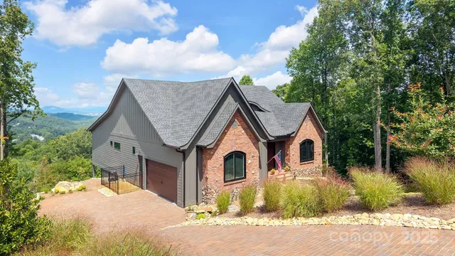 a view of a white house with a yard plants and large tree