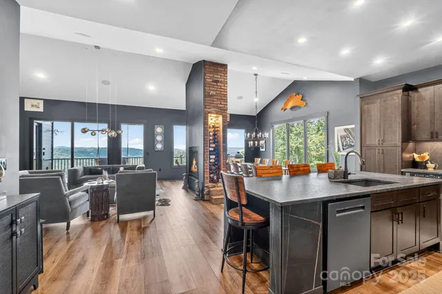 a kitchen with stainless steel appliances granite countertop a stove top oven a sink dishwasher a dining table and chairs with wooden floor