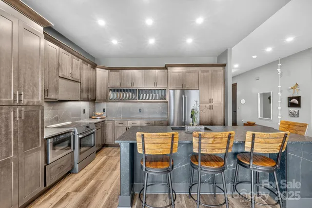 a kitchen with stainless steel appliances kitchen island granite countertop a stove a sink and a refrigerator