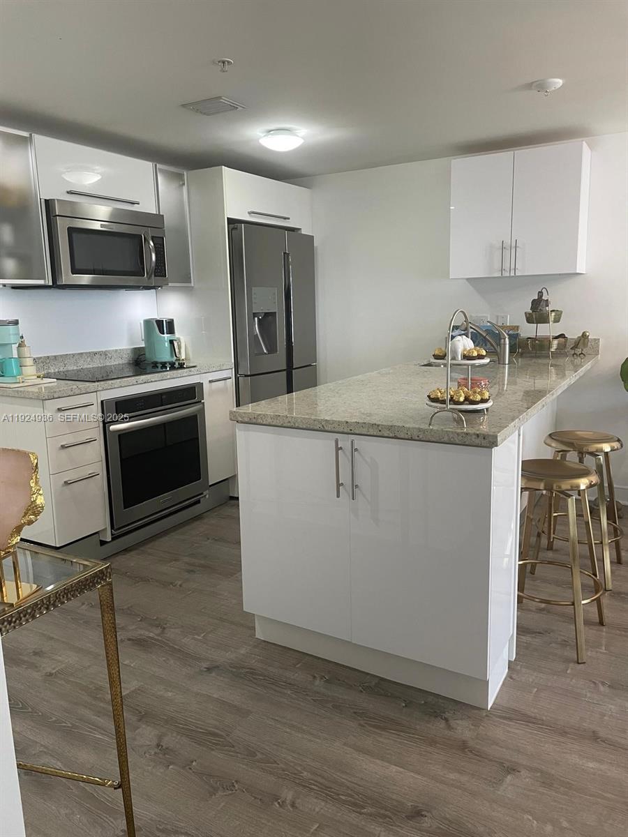 185 Southwest 7th Street, Unit 2014 Miami, FL 33130 - Photo 19 of 38 a kitchen with stainless steel appliances granite countertop a stove top oven a sink a refrigerator white cabinets and wooden floor