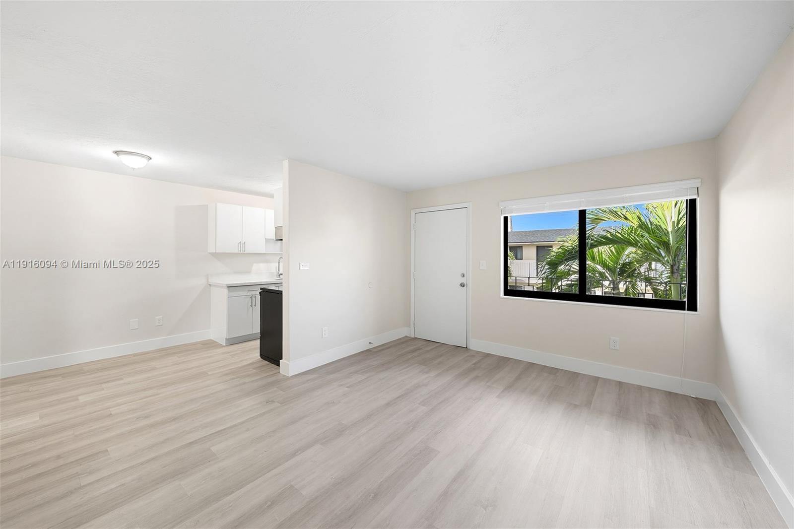 a view of empty room with wooden floor and window