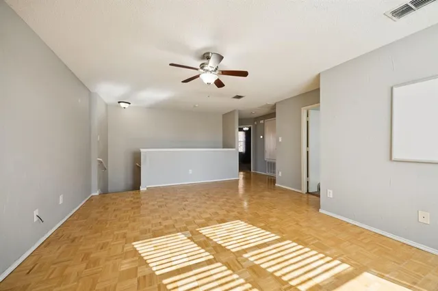 an empty room with a ceiling fan and windows