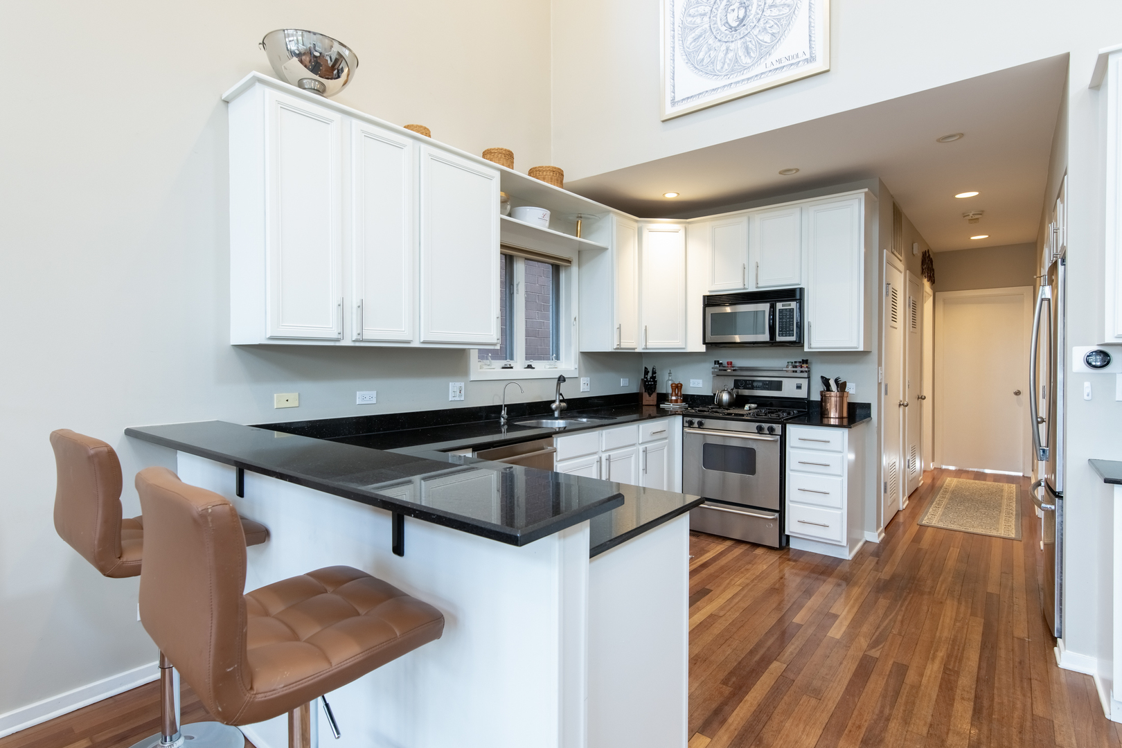 1409 West Huron Street, Unit 3 Chicago, IL 60642 - Photo 12 of 42 a kitchen with granite countertop a stove a sink a microwave and wooden cabinets