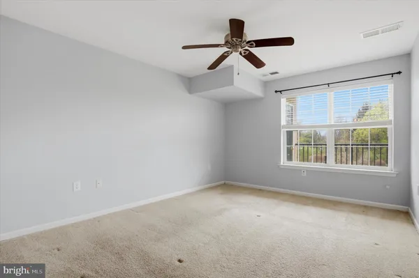 a view of a big room with windows and ceiling fan