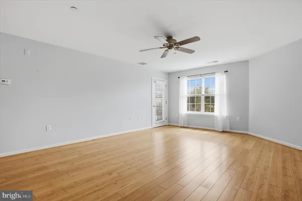 a view of empty room with wooden floor and ceiling fan