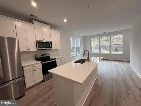 a kitchen with a refrigerator a stove top oven a sink dishwasher and wooden floor