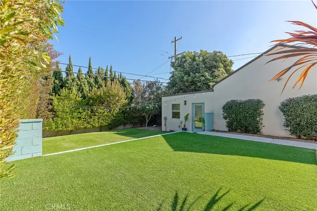 a view of a white house next to a yard with a tree