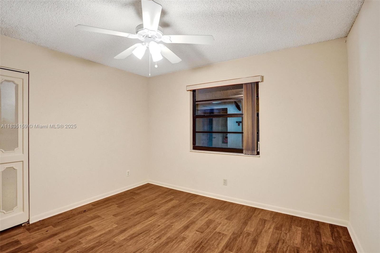 4965 East Sabal Palm Boulevard, Unit 207 Tamarac, FL 33319 - Photo 14 of 37 an empty room with wooden floor chandelier fan and windows