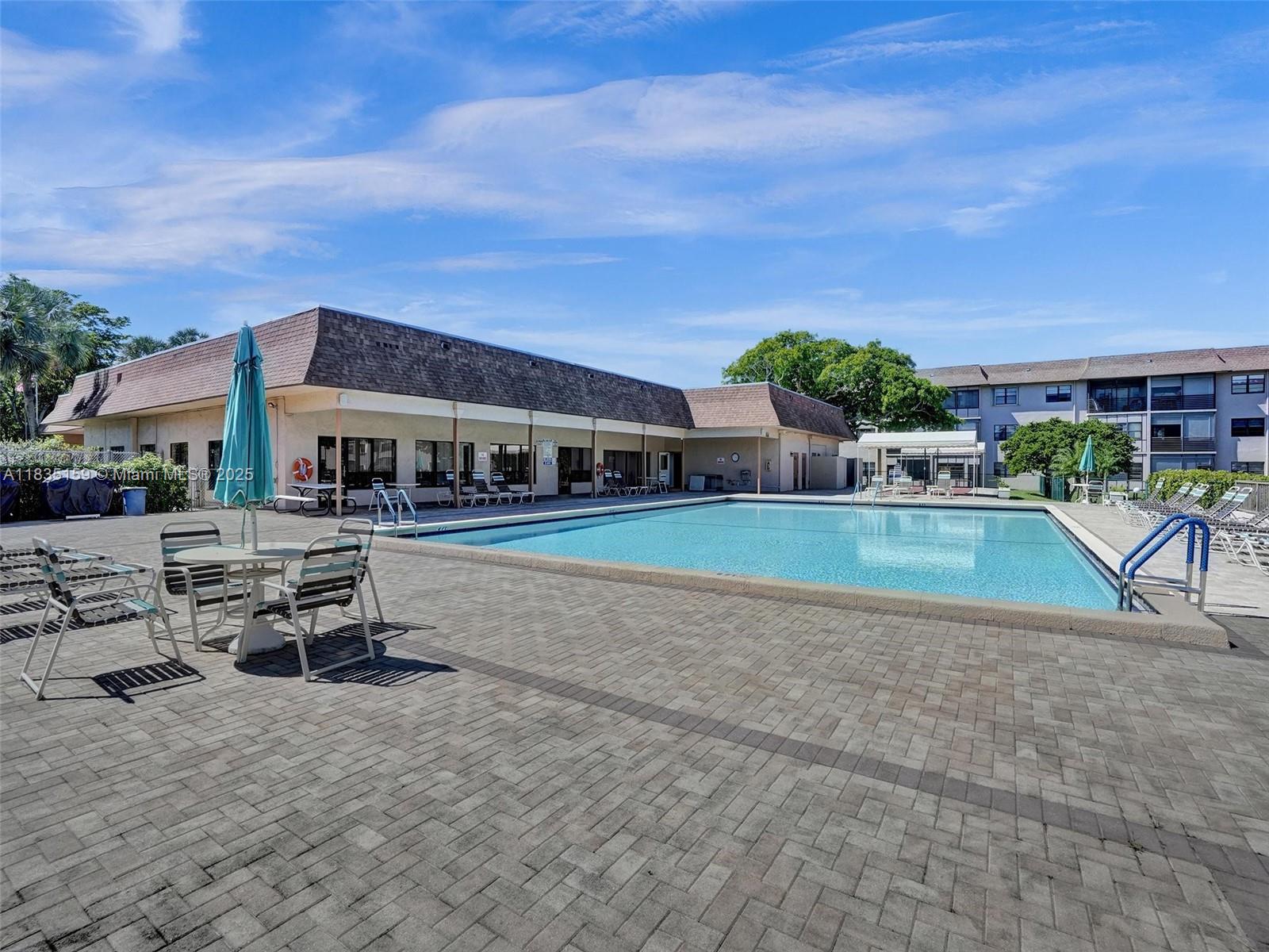 4965 East Sabal Palm Boulevard, Unit 207 Tamarac, FL 33319 - Photo 30 of 37 a view of a swimming pool with lawn chairs and plants