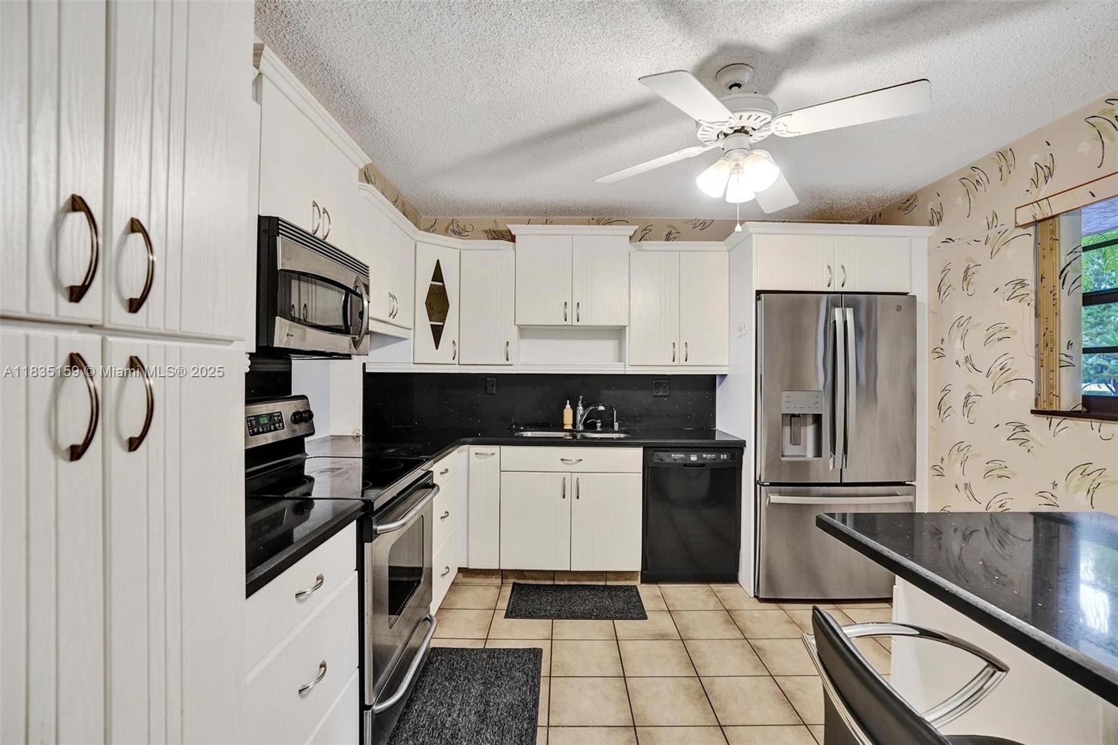 4965 East Sabal Palm Boulevard, Unit 207 Tamarac, FL 33319 - Photo 8 of 37 a kitchen with a refrigerator and a sink
