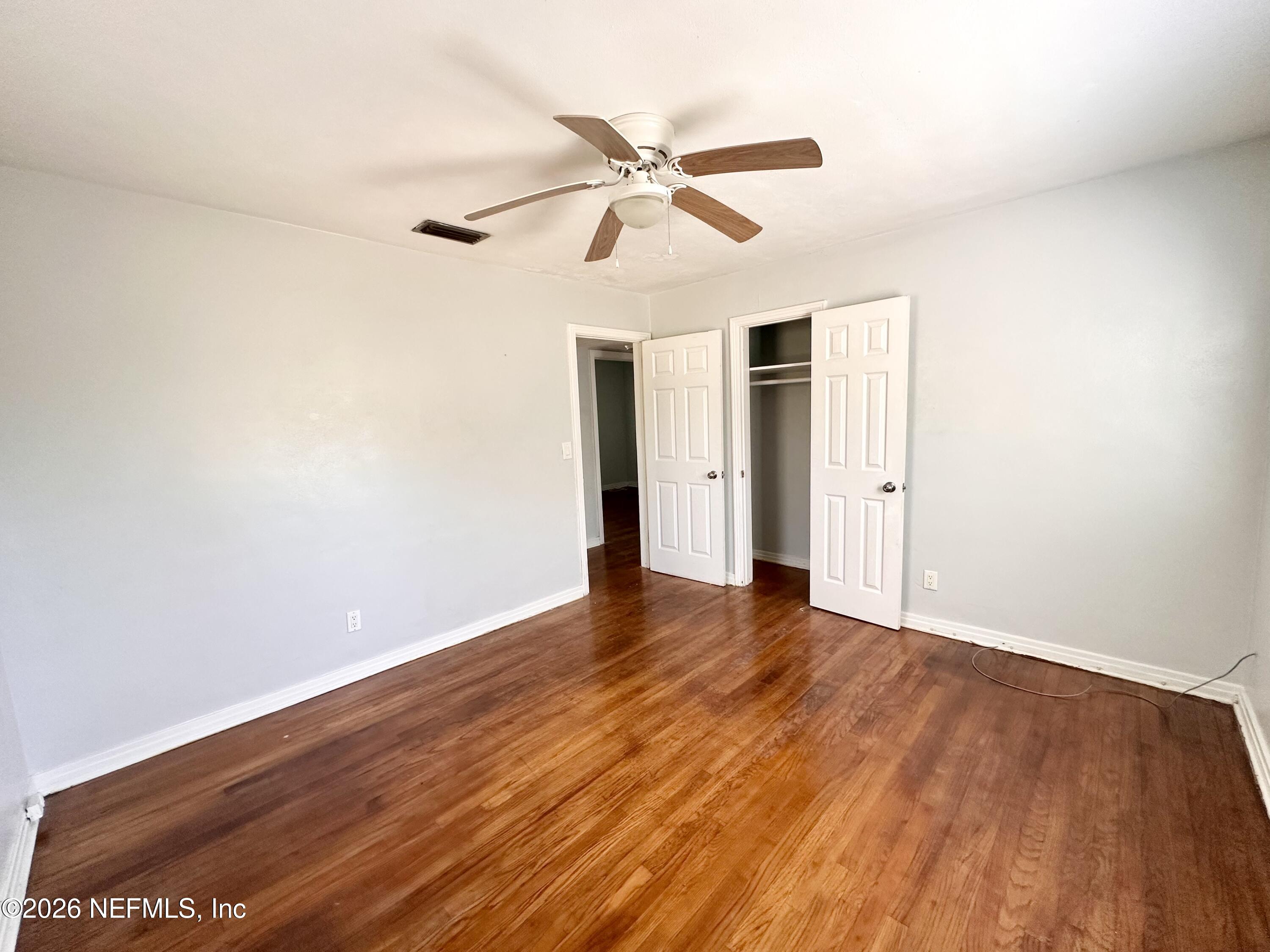 3638 Jammes Road Jacksonville, FL 32210 - Photo 19 of 31 a view of an empty room with wooden floor and a ceiling fan
