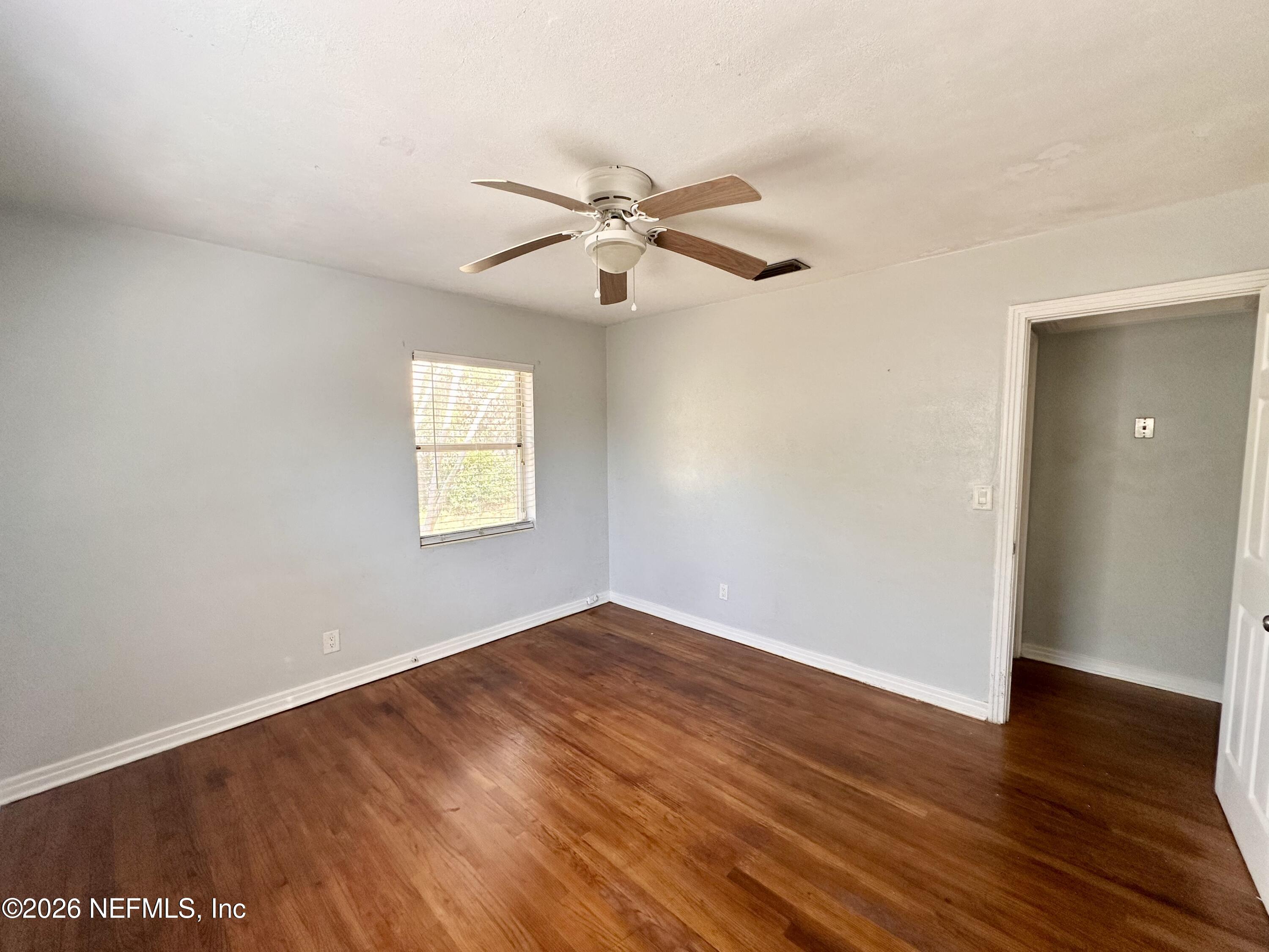 3638 Jammes Road Jacksonville, FL 32210 - Photo 20 of 31 an empty room with wooden floor ceiling fan and windows