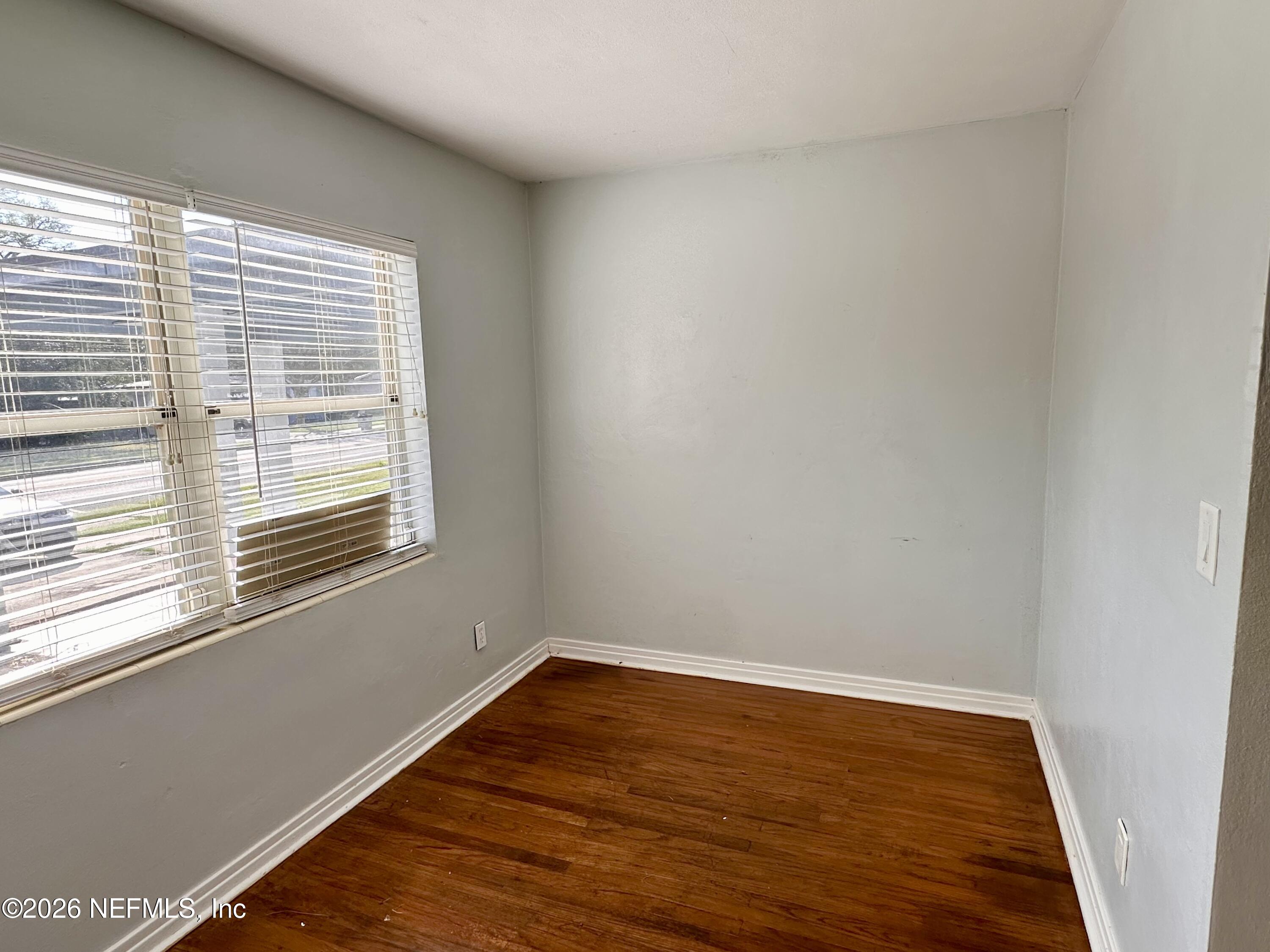 3638 Jammes Road Jacksonville, FL 32210 - Photo 9 of 31 a view of an empty room with wooden floor and a window