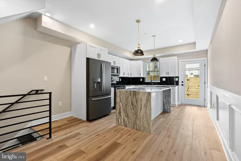 a large kitchen with a center island wooden floor stainless steel appliances and cabinets