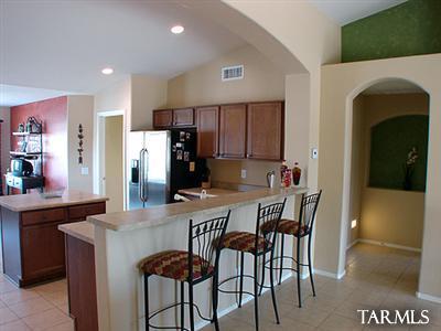 62195 East Northwood Road Tucson, AZ 85739 - Photo 10 of 25 a kitchen with stainless steel appliances a dining table chairs and refrigerator
