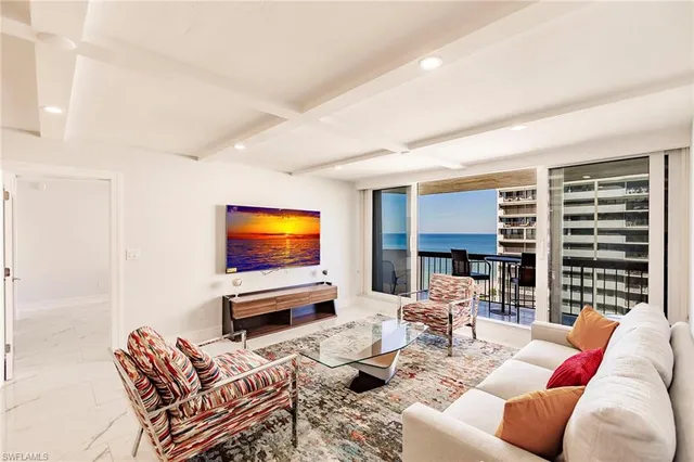 a living room with furniture a flat screen tv and floor to ceiling window