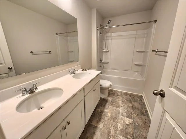 a bathroom with a double vanity sink toilet mirror and shower