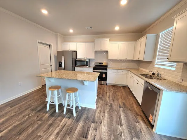 a white kitchen with wooden floors and stainless steel appliances