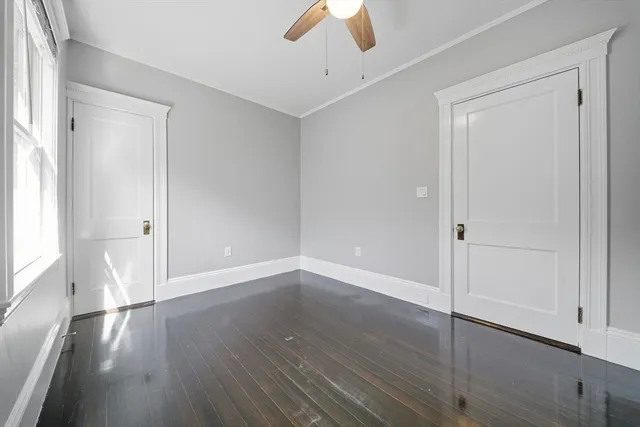 an empty room with wooden floor cabinet and windows