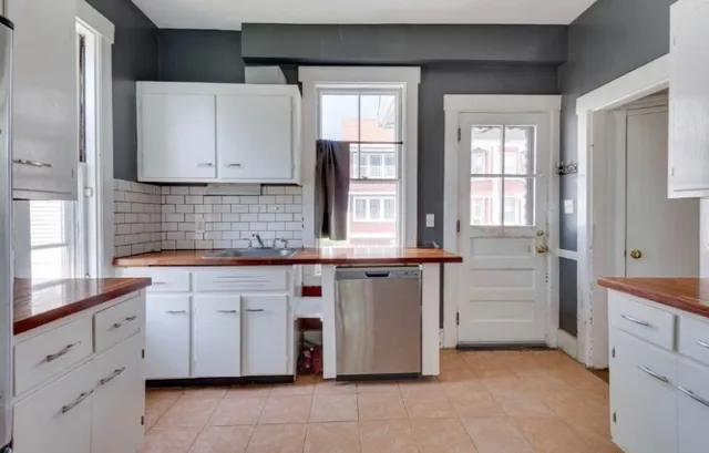 a kitchen with white cabinets and sink