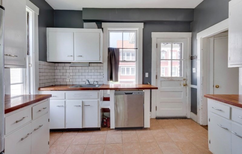 a kitchen with white cabinets and sink