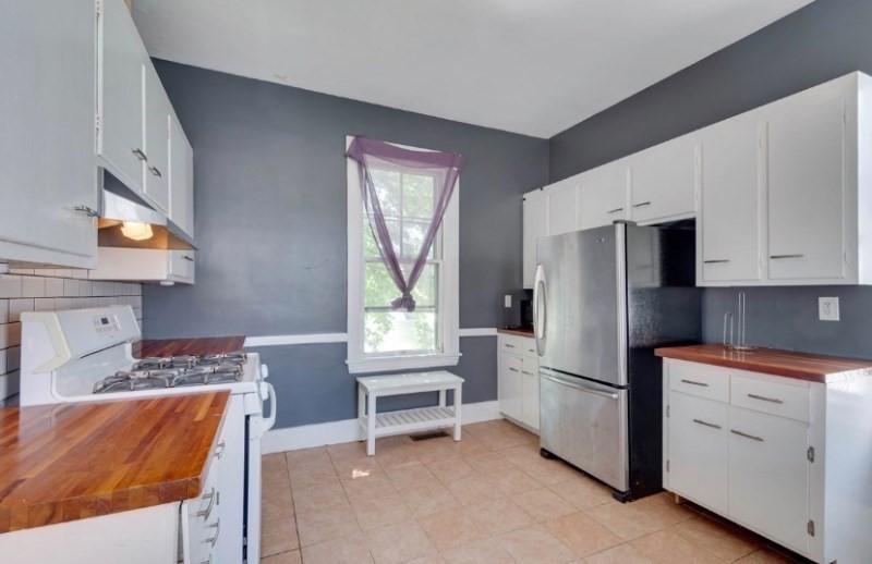 12 Fiske Street, Unit 1 Waltham, MA 02451 - Photo 3 of 18 a kitchen with stainless steel appliances kitchen island granite countertop a refrigerator stove oven and white cabinets