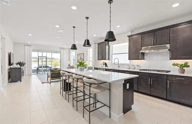 a kitchen with stainless steel appliances kitchen island granite countertop a table chairs and a refrigerator