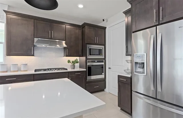 a large kitchen with a counter space a sink appliances and a large window