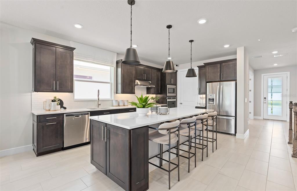 6249 Dew Drop Loop St. Cloud, FL 34771 - Photo 10 of 26 a kitchen with stainless steel appliances kitchen island granite countertop a stove a sink and a refrigerator