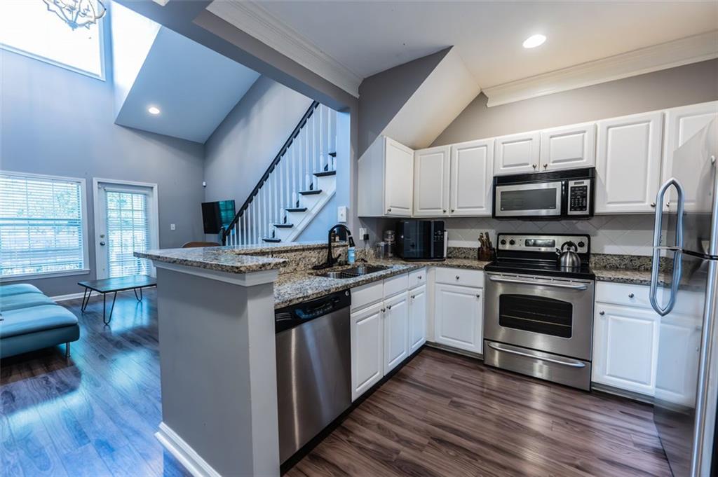 a kitchen with granite countertop a stove top oven a sink dishwasher a dining table and chairs with wooden floor