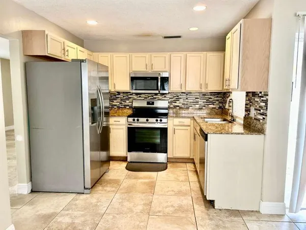 a kitchen with stainless steel appliances granite countertop a stove a refrigerator and a sink
