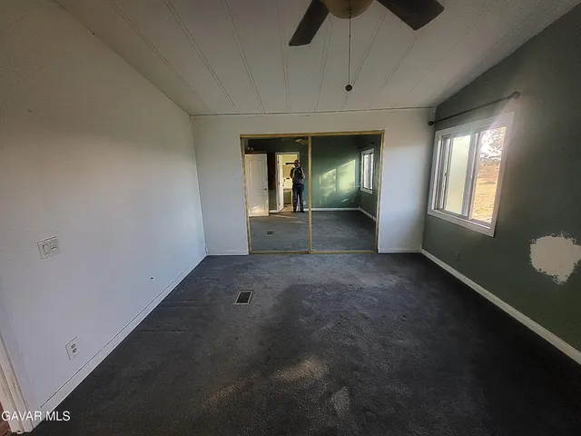 an empty room with chandelier fan and windows