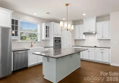 a kitchen with stainless steel appliances granite countertop a sink a stove a refrigerator and island with wooden floor