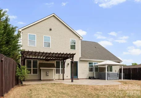 a view of a white house with a small yard and wooden fence