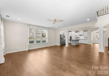 an empty room with wooden floor fireplace and windows