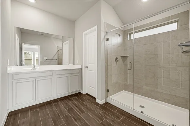 a bathroom with a double vanity sink a mirror and a glass door shower