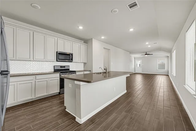 a large white kitchen with wooden floors and stainless steel appliances