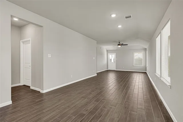 an empty room with wooden floor and windows