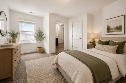 a spacious bedroom with a bed a mirror and a potted plant