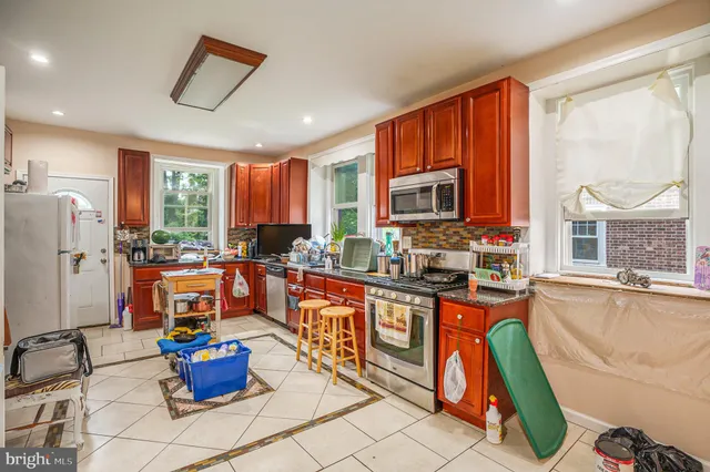 a living room with furniture a flat screen tv and a refrigerator