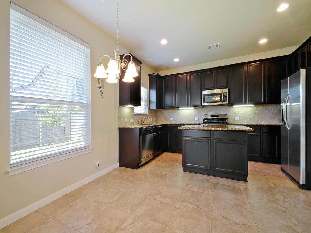 8508 Inca Dove Drive Austin, TX 78729 - Photo 3 of 22 a kitchen with kitchen island granite countertop a stove top oven a sink and a refrigerator