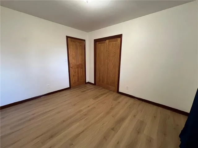 a view of an empty room with wooden floor and closet