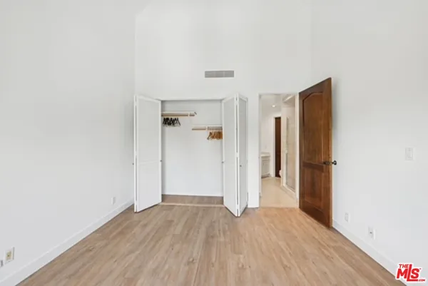 a view of an empty room with wooden floor and a bathroom