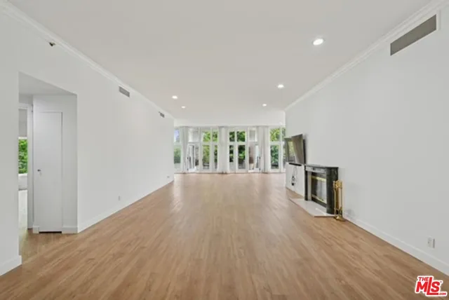 a view of a big room with wooden floor and windows