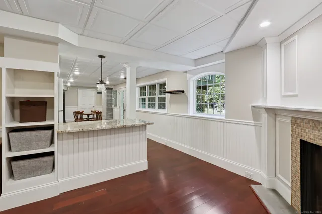 a living room with stainless steel appliances wooden floor and a fireplace